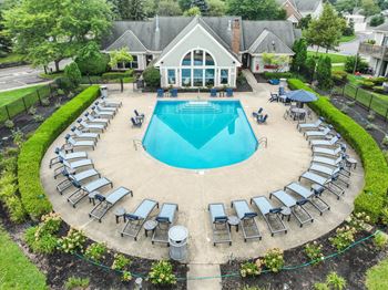 a pool with lounge chairs and umbrellas in front of a house